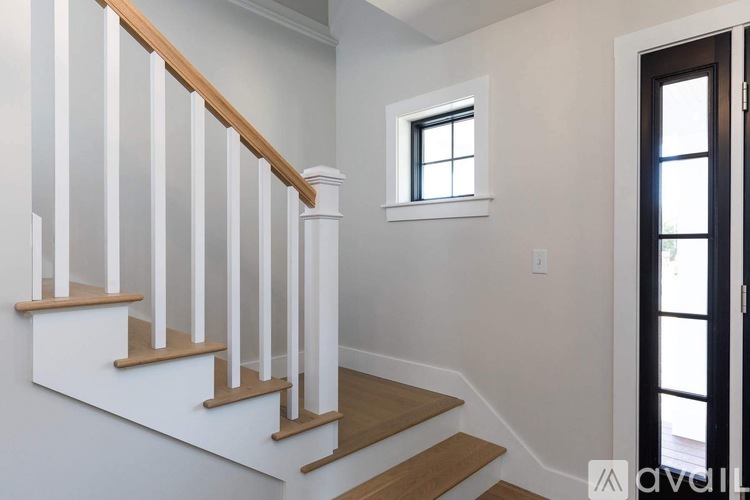 A staircase with white railings and wooden steps leads to a door.