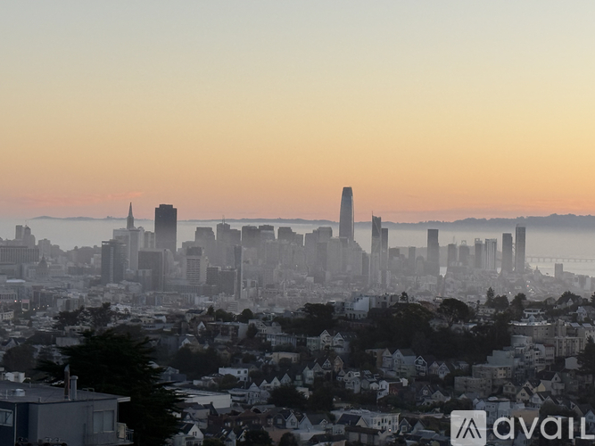 A cityscape with a mix of residential and commercial buildings, with the sun setting in the background.