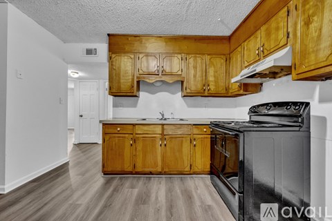 A kitchen with wooden cabinets and a black stove top oven.
