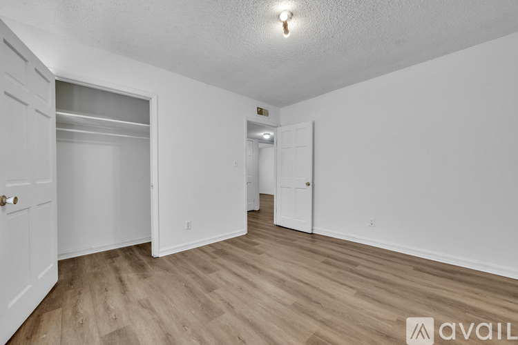 A spacious room with wooden flooring and white walls.