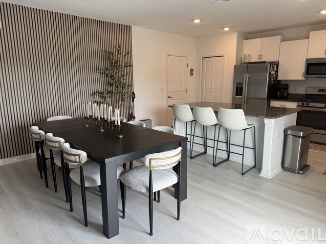 A modern dining room with a black table and white chairs.