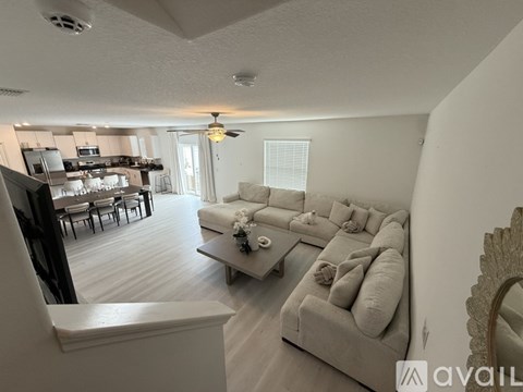 A living room with a grey couch and a dining table with chairs.