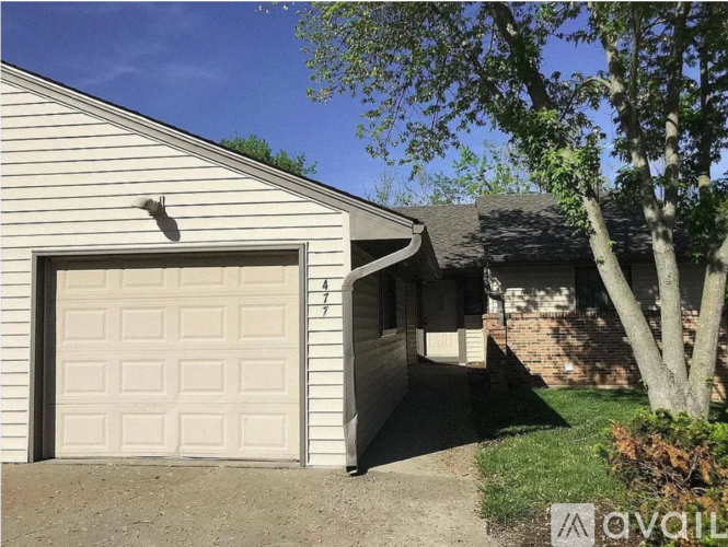 A white garage door is on the left side of a house.