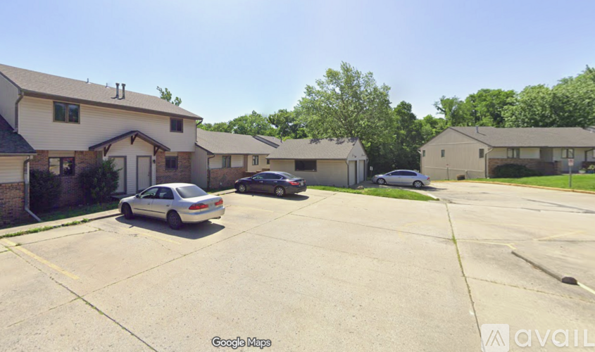 A car is parked in a parking lot with other cars and houses in the background.