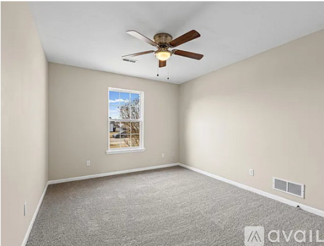 A room with a ceiling fan and a window showing a tree outside.