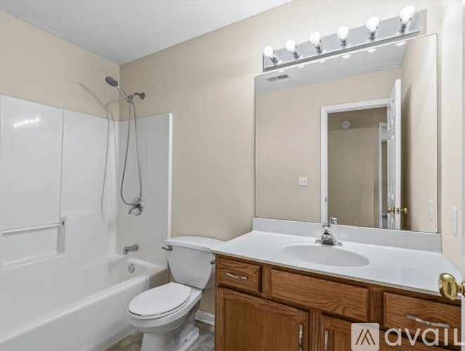 A bathroom with a white toilet, sink, and a mirror with lights above it.