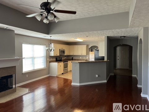 A spacious living room with a fireplace and a kitchen area in the background.