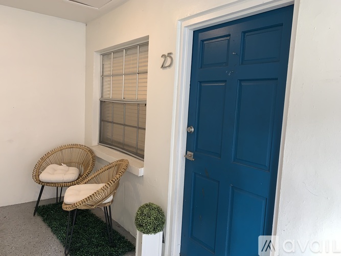 A room with a blue door and two wicker chairs.