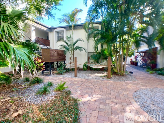 A sunny day at a residential area with a house, trees, and a brick pathway.