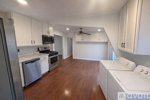 A kitchen with white cabinets and a wooden floor.