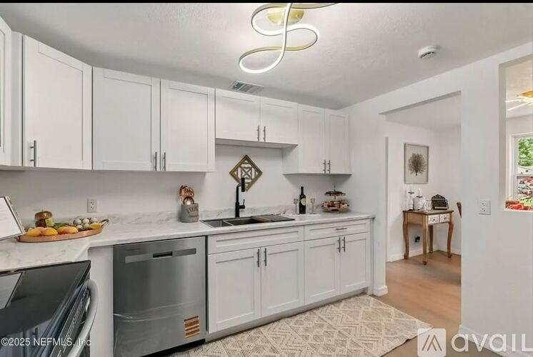 A kitchen with white cabinets and a marble countertop.