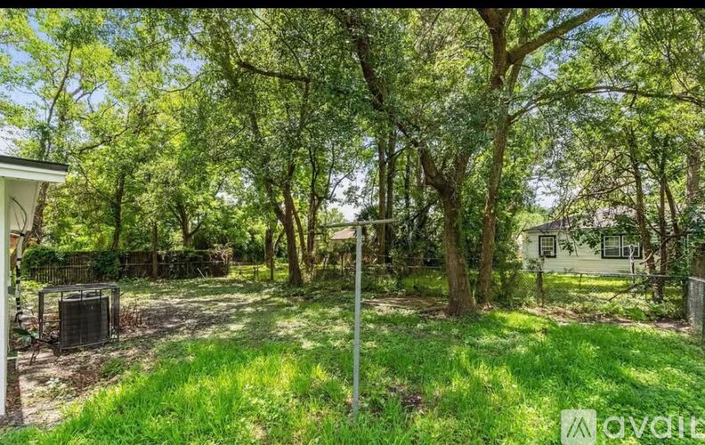 A lush green backyard with a white house and a mailbox.