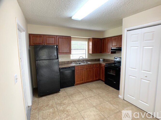 A kitchen with brown cabinets and black appliances.