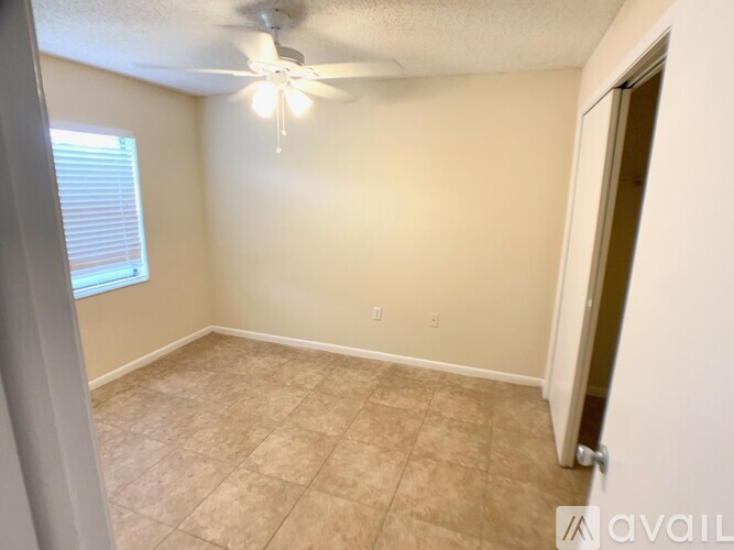 A room with beige walls and a ceiling fan.
