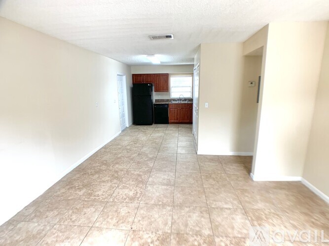 A long, empty hallway with a black refrigerator in the distance.
