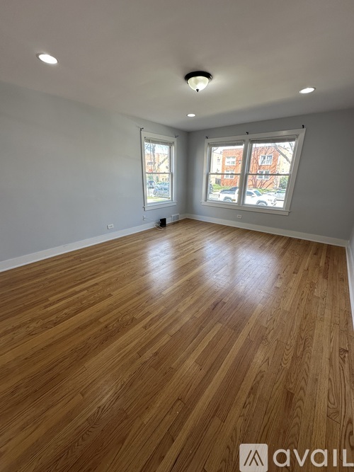 A room with wooden flooring and a window showing a view of a building.