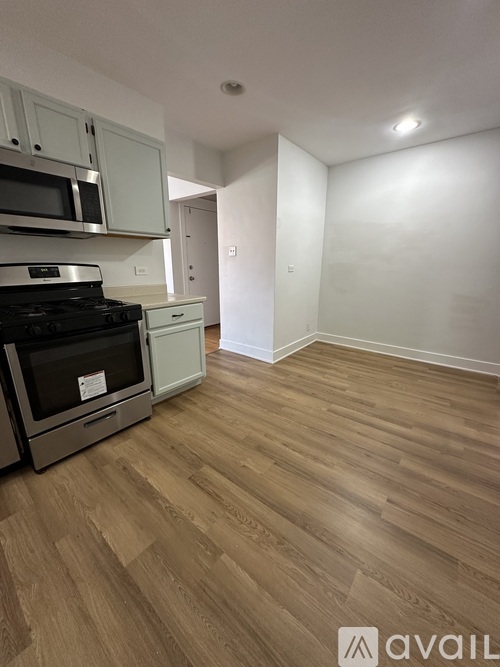 A kitchen with a stove top oven and wooden flooring.