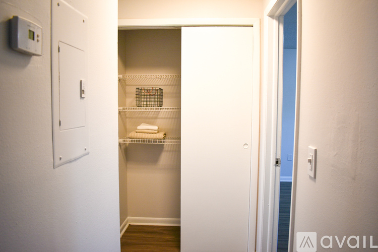 A small white closet with a wire shelf and a door.