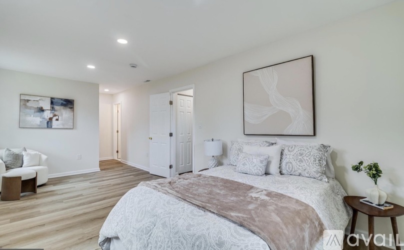 A bedroom with a large bed and a painting on the wall.
