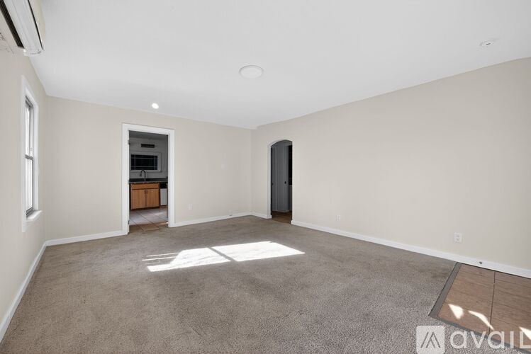 A spacious room with a carpeted floor and a door on the right side.