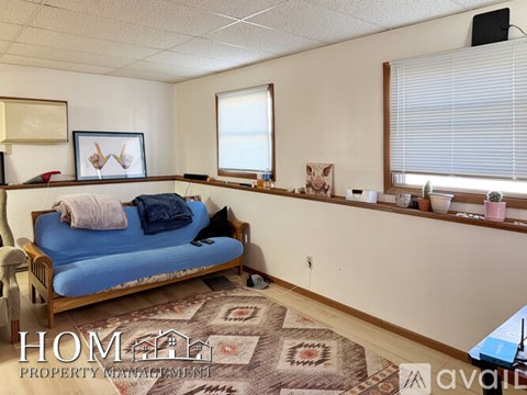 A living room with a blue couch and a rug.
