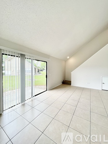 A spacious room with a tiled floor and a sliding glass door leading to a backyard.