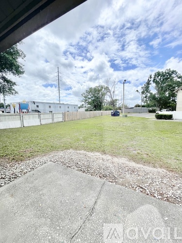 A grassy area with a concrete slab in the foreground and a fence in the background.