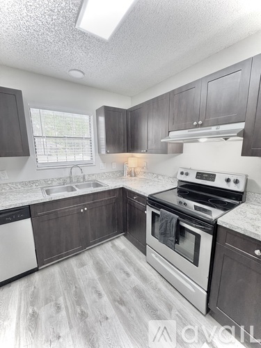 A kitchen with a stove, sink, and cabinets.