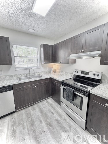 A kitchen with a stove, sink, and cabinets.