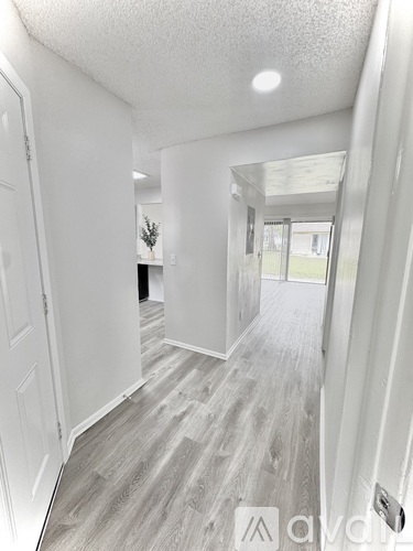 A hallway with white walls and grey flooring.