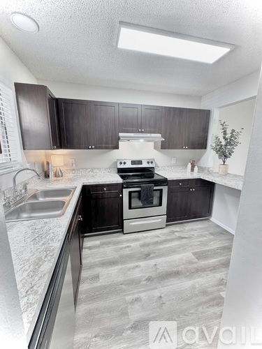 A kitchen with a stove, sink, and cabinets.