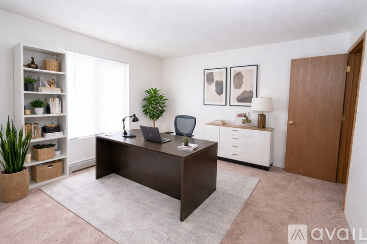 A room with a desk, laptop, and a potted plant.
