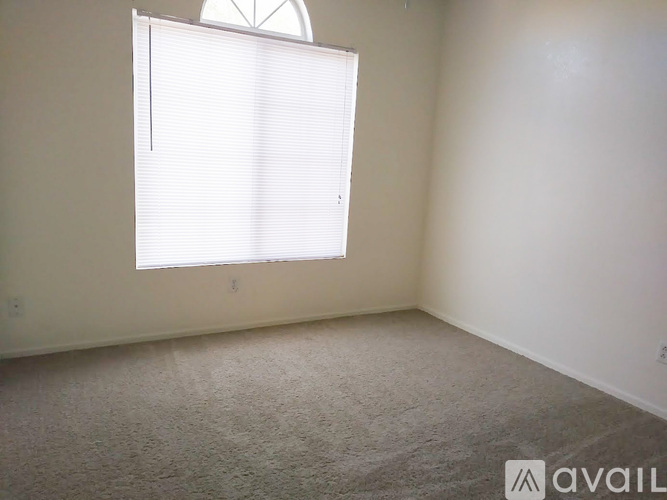 A room with a window covered by white blinds.