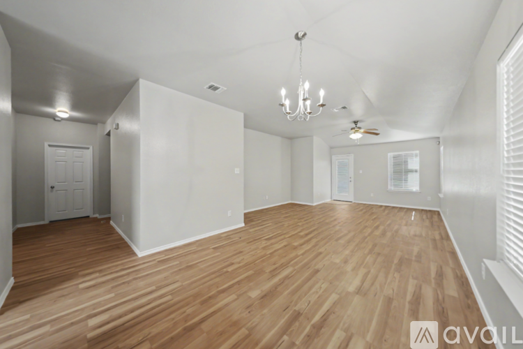 A spacious room with wooden flooring and white walls.