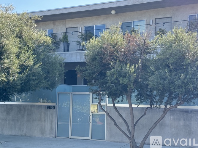 A building with a number 9100 on the wall and a tree in front of it.