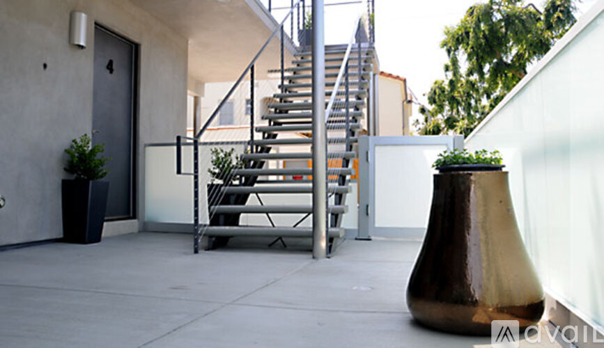 A brown vase is on a patio with a staircase in the background.