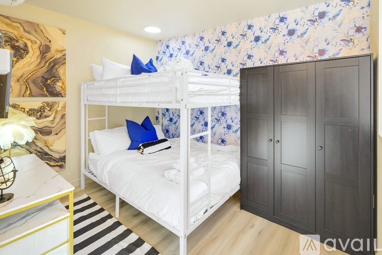 A bedroom with a white bunk bed and a black wardrobe.