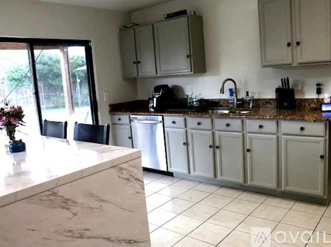 A kitchen with white cabinets and a marble countertop.