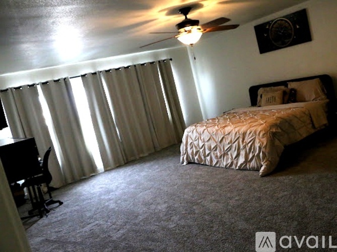 A bedroom with a bed, chair, and window with curtains.
