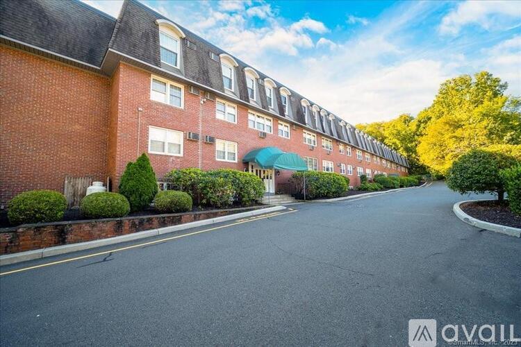 A street view of a residential area with apartment buildings and a clear sky.