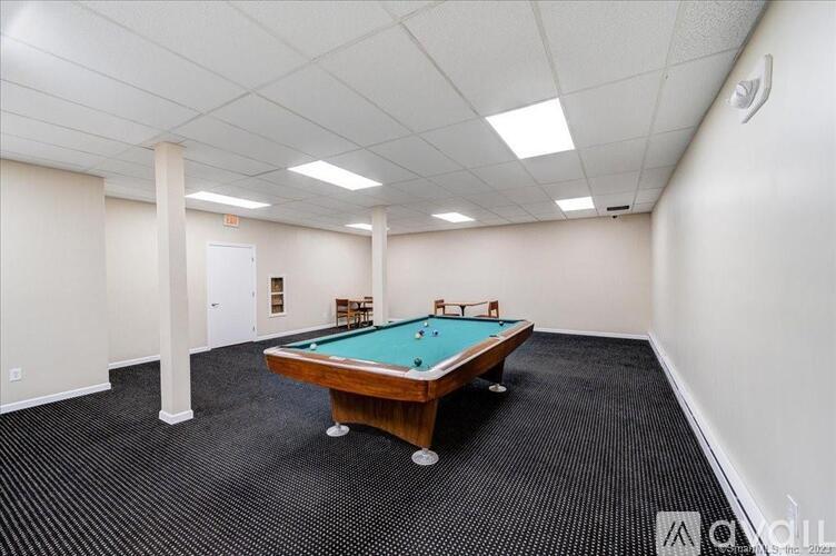 A pool table is in a room with white walls and a carpeted floor.
