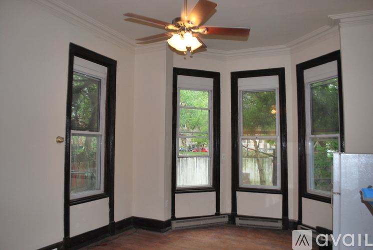 A room with a ceiling fan and three windows.
