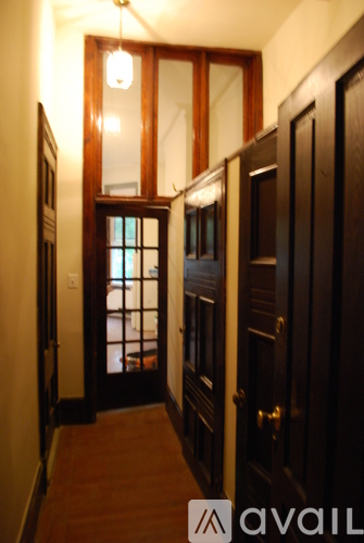 A hallway with a wooden floor and dark wood doors.