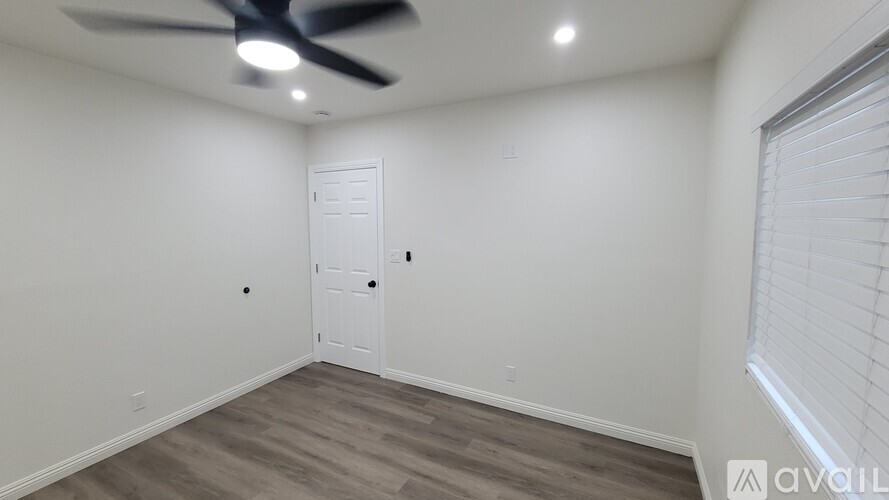 A room with a ceiling fan and a door.