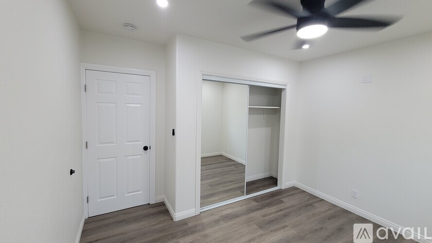 A room with a white door and a fan on the ceiling.