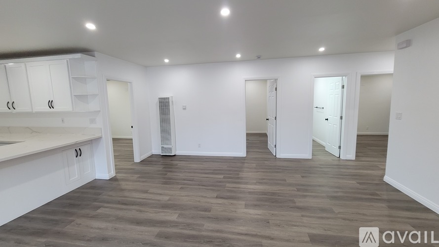 A spacious room with wooden flooring and white walls.