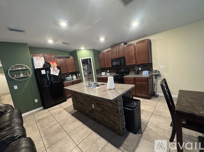 A kitchen with a black fridge and a black counter top.