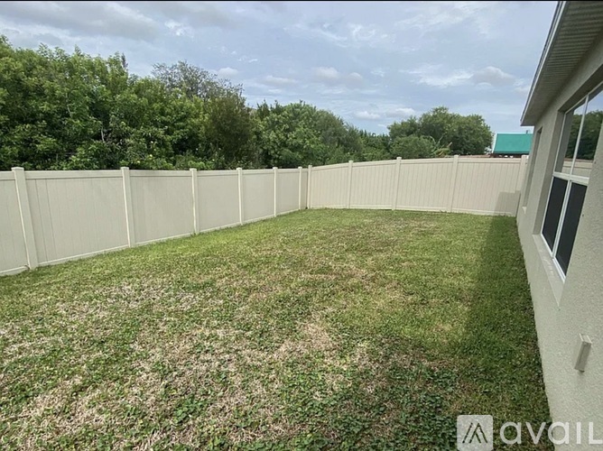A backyard with a white fence and green grass.