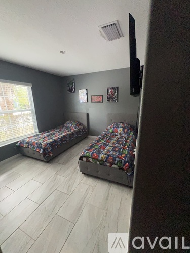 A bedroom with two beds and a flat screen TV mounted on the wall.