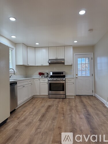 A kitchen with white cabinets and a wooden floor.